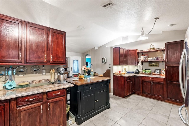 kitchen featuring lofted ceiling, light tile patterned flooring, a textured ceiling, and light stone counters