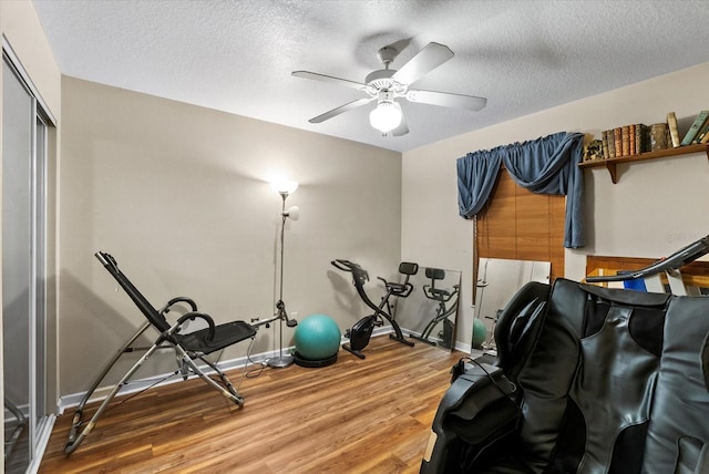 exercise room featuring a textured ceiling, ceiling fan, and wood-type flooring