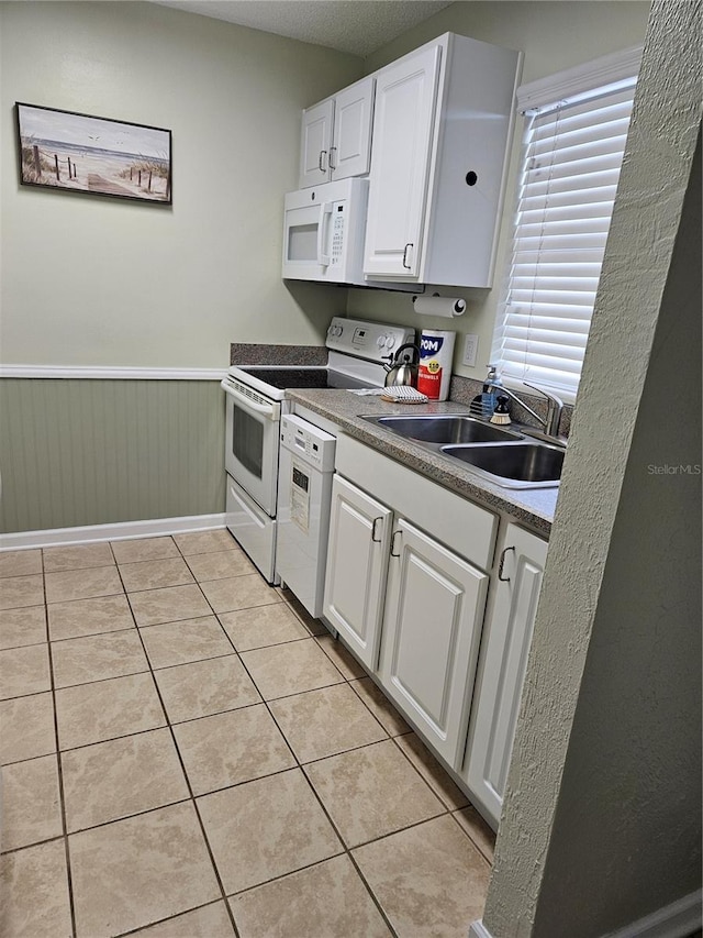 kitchen featuring white cabinetry, white appliances, a textured ceiling, light tile patterned floors, and sink