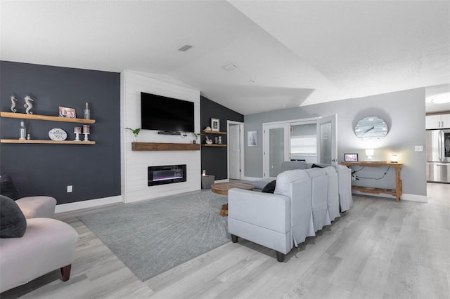 living room featuring light wood-type flooring, lofted ceiling, and a large fireplace