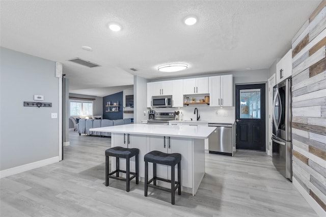 kitchen with a kitchen island, appliances with stainless steel finishes, a textured ceiling, and white cabinetry