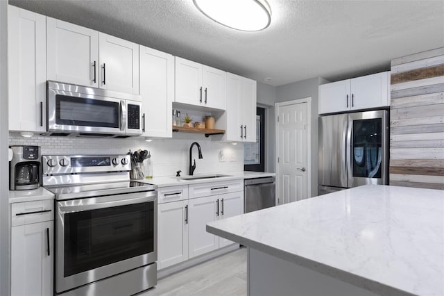 kitchen featuring light hardwood / wood-style floors, a textured ceiling, sink, white cabinets, and stainless steel appliances