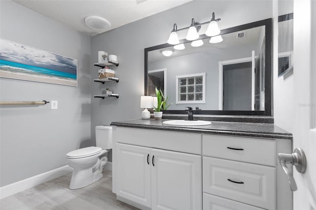 bathroom featuring vanity, toilet, a textured ceiling, and hardwood / wood-style flooring