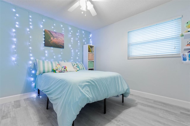 bedroom with ceiling fan, hardwood / wood-style flooring, and a textured ceiling