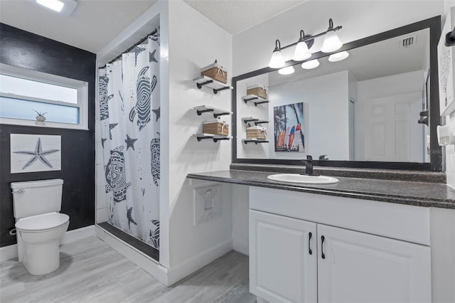 bathroom with vanity, curtained shower, a textured ceiling, hardwood / wood-style flooring, and toilet