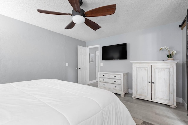 bedroom featuring light wood-type flooring, a textured ceiling, and ceiling fan