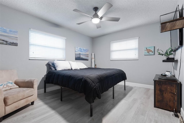 bedroom with light hardwood / wood-style flooring, ceiling fan, and a textured ceiling