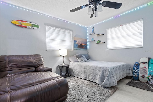 bedroom featuring light hardwood / wood-style floors, ceiling fan, and a textured ceiling