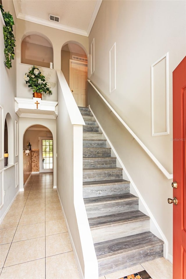 stairway featuring crown molding and tile patterned flooring