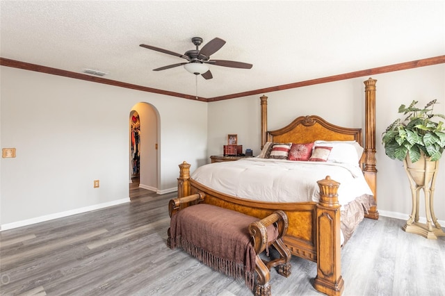 bedroom featuring ceiling fan, hardwood / wood-style floors, crown molding, and a textured ceiling