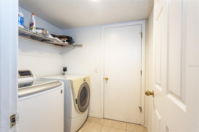 laundry room with independent washer and dryer, a textured ceiling, and light tile patterned floors