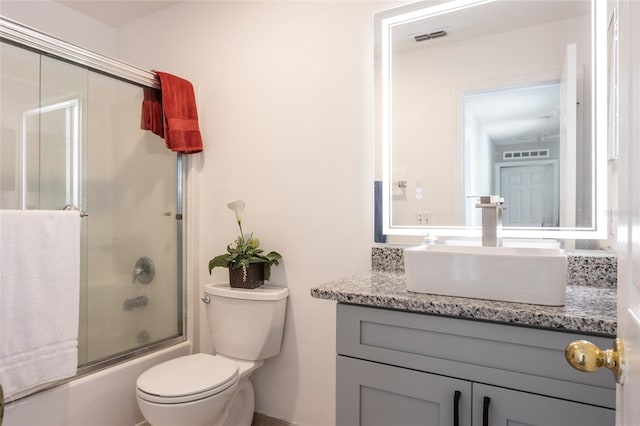 full bathroom with vanity, toilet, and bath / shower combo with glass door