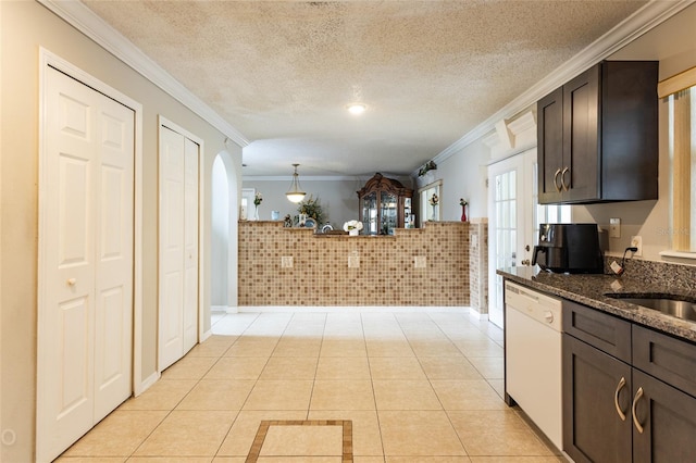 kitchen with dark brown cabinetry, white dishwasher, dark stone counters, and light tile patterned floors