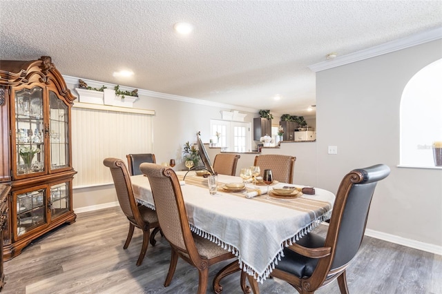 dining area with hardwood / wood-style floors, a textured ceiling, and ornamental molding