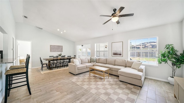 living area with visible vents, a ceiling fan, baseboards, light wood finished floors, and lofted ceiling