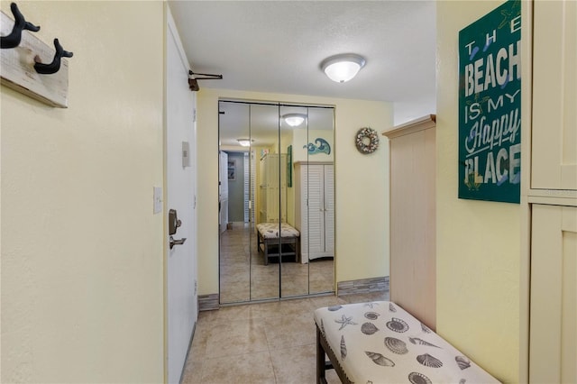 hallway with a textured ceiling and light tile patterned flooring