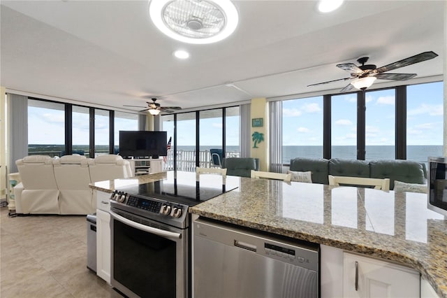 kitchen with white cabinets, appliances with stainless steel finishes, ceiling fan, and light stone countertops