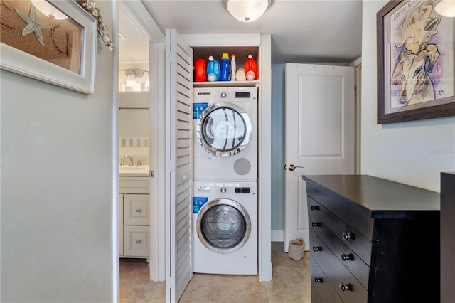 laundry area featuring stacked washer / dryer, sink, and light tile patterned flooring