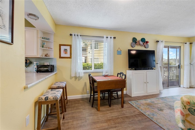 dining area with light hardwood / wood-style flooring, plenty of natural light, and a textured ceiling