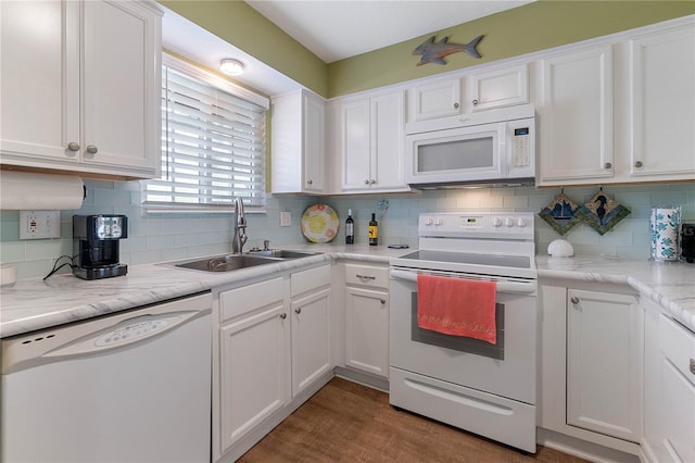 kitchen featuring white appliances, sink, decorative backsplash, dark wood-type flooring, and white cabinets