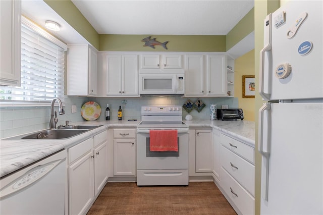 kitchen with white appliances, backsplash, white cabinetry, and sink