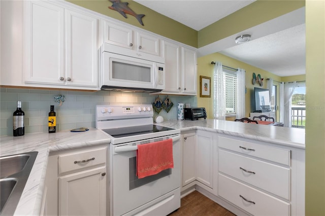 kitchen featuring white appliances, kitchen peninsula, decorative backsplash, dark hardwood / wood-style floors, and white cabinets