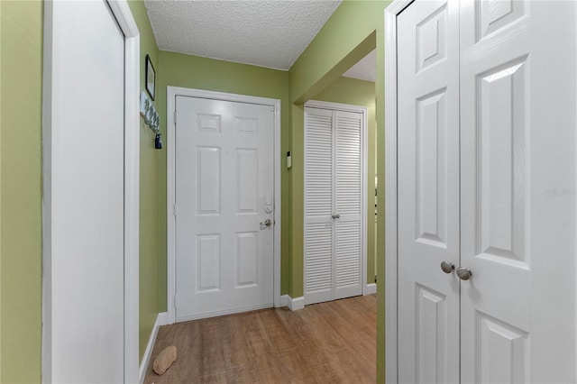 hallway with a textured ceiling and light hardwood / wood-style floors