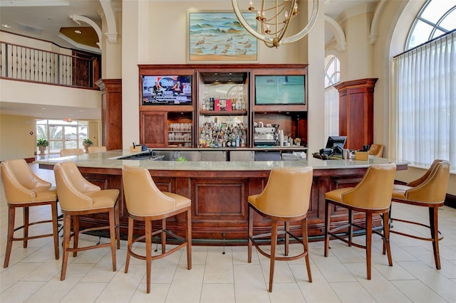 bar with a high ceiling, light tile patterned flooring, and a notable chandelier