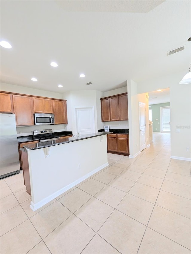 kitchen featuring appliances with stainless steel finishes, light tile patterned flooring, a kitchen island, and pendant lighting