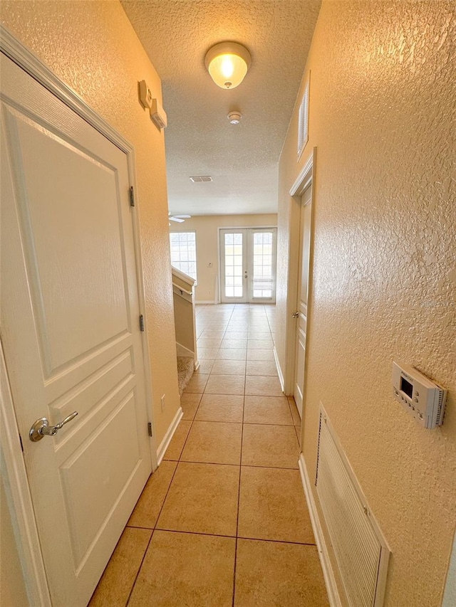 hallway featuring a textured ceiling and light tile patterned floors