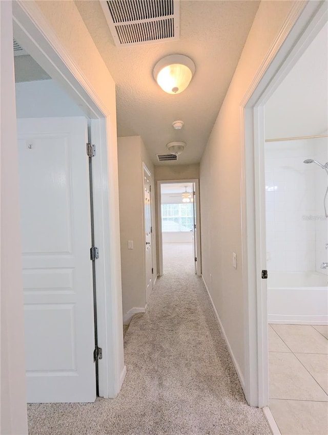 hall featuring a textured ceiling and light carpet