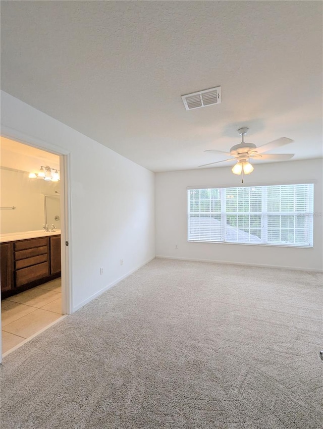 carpeted spare room featuring ceiling fan and a textured ceiling