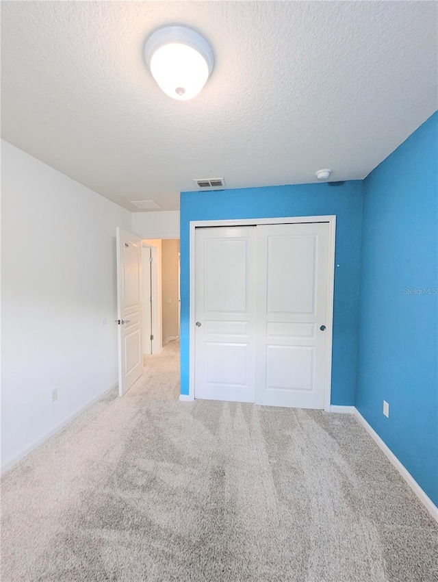 unfurnished bedroom with a closet, carpet flooring, and a textured ceiling