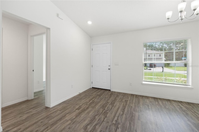 unfurnished room with vaulted ceiling, dark hardwood / wood-style floors, and a chandelier