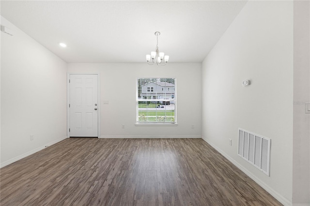 spare room with dark hardwood / wood-style floors and a chandelier