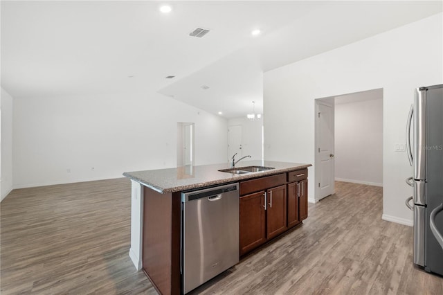 kitchen with light wood-type flooring, sink, an island with sink, vaulted ceiling, and appliances with stainless steel finishes