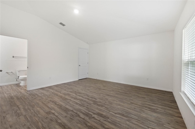 unfurnished room with a healthy amount of sunlight, vaulted ceiling, and dark hardwood / wood-style flooring