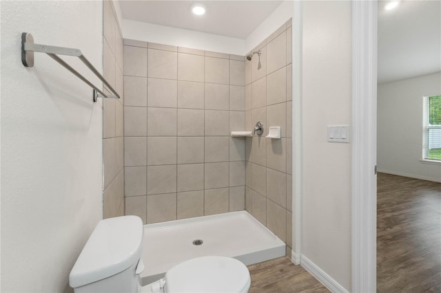 bathroom with hardwood / wood-style floors, tiled shower, and toilet