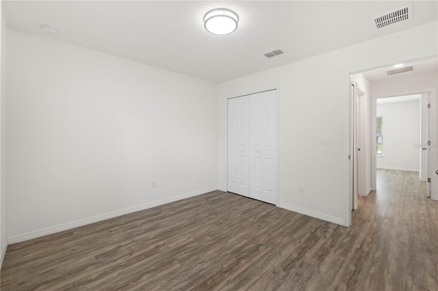 unfurnished bedroom featuring dark hardwood / wood-style floors and a closet