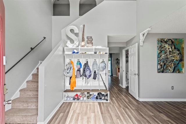 mudroom with wood-type flooring and a towering ceiling