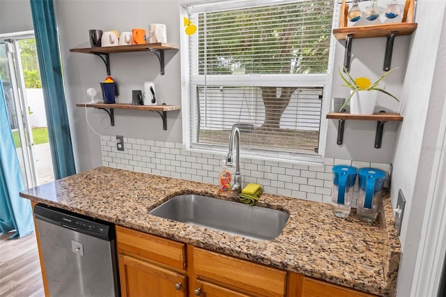 kitchen with sink, backsplash, dishwasher, light stone countertops, and light hardwood / wood-style floors