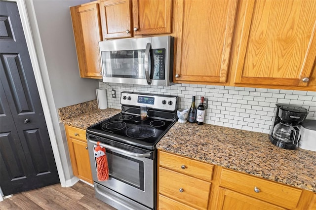 kitchen with appliances with stainless steel finishes, stone counters, light hardwood / wood-style floors, and tasteful backsplash