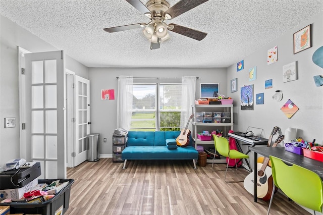 game room with a textured ceiling, ceiling fan, and light hardwood / wood-style flooring