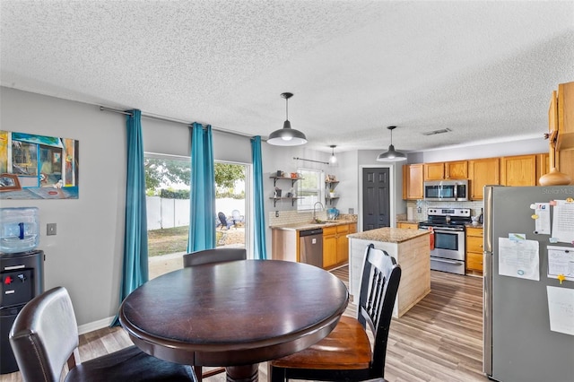 dining space with a textured ceiling, light hardwood / wood-style floors, and sink