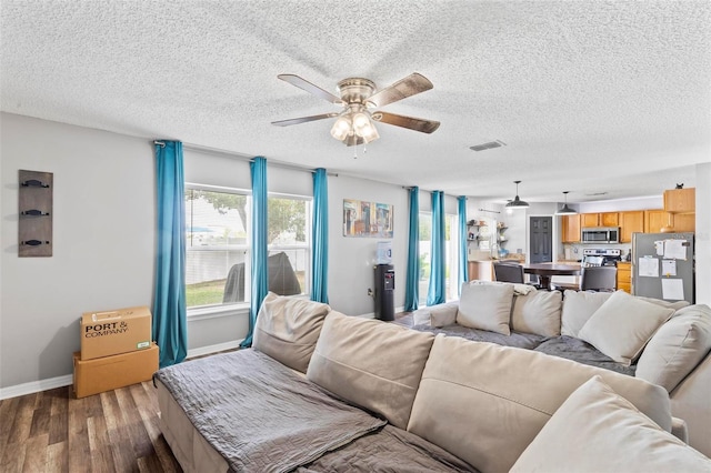 living room with a textured ceiling, ceiling fan, and dark wood-type flooring