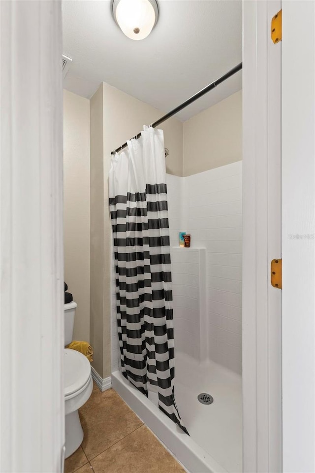 bathroom with toilet, a shower with shower curtain, and tile patterned floors