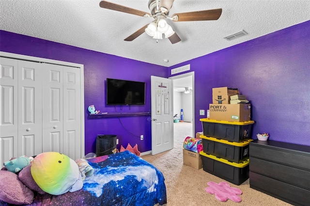 bedroom with ceiling fan, light colored carpet, a textured ceiling, and a closet