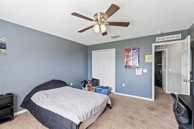 carpeted bedroom with a textured ceiling, ceiling fan, and a closet