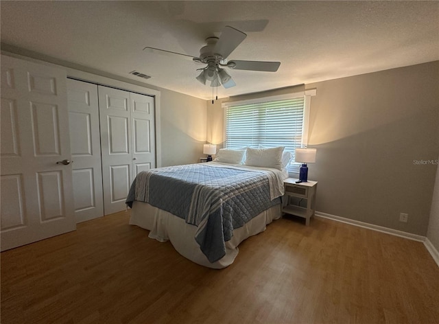 bedroom featuring a closet, ceiling fan, wood-type flooring, and a textured ceiling