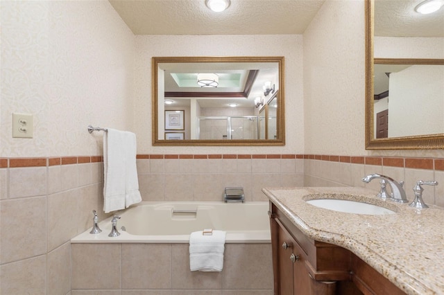 bathroom with tile walls, a textured ceiling, independent shower and bath, backsplash, and vanity